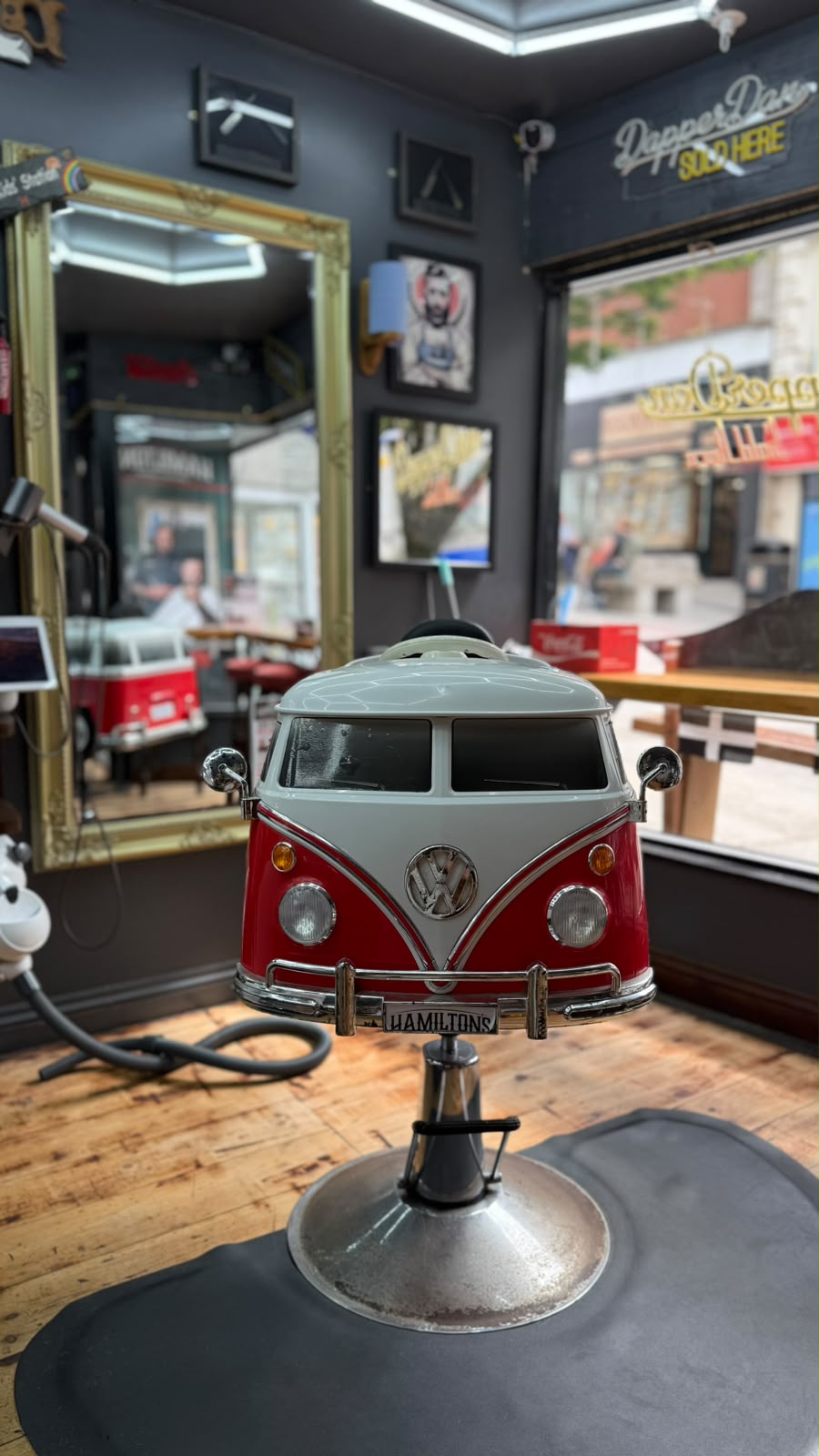 Red and white VW campervan children's barber chair beside the window at Hamilton's Barbershop